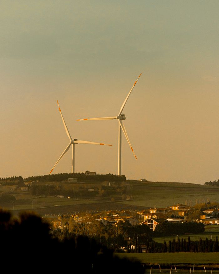 Scenic view of wind turbines on a hill near a rural village, capturing renewable energy beauty.